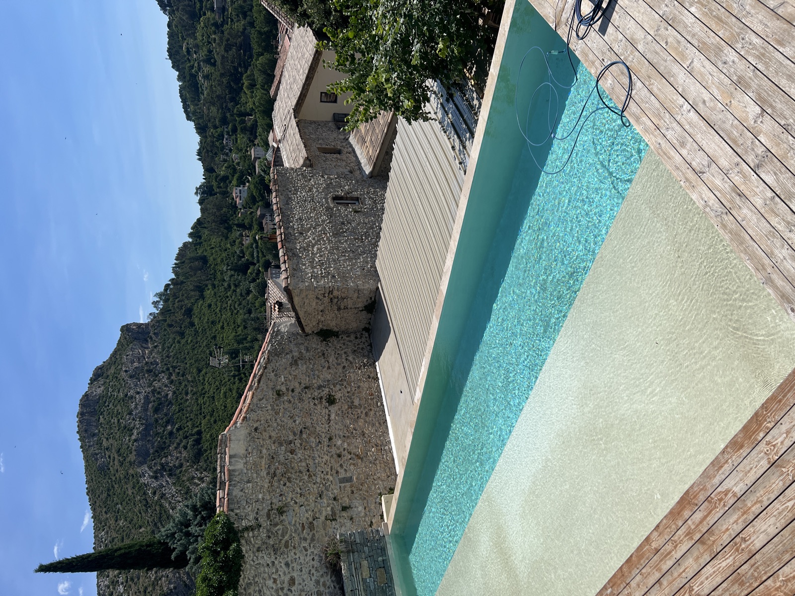 Terrasse en bois de la piscine et mas en pierre